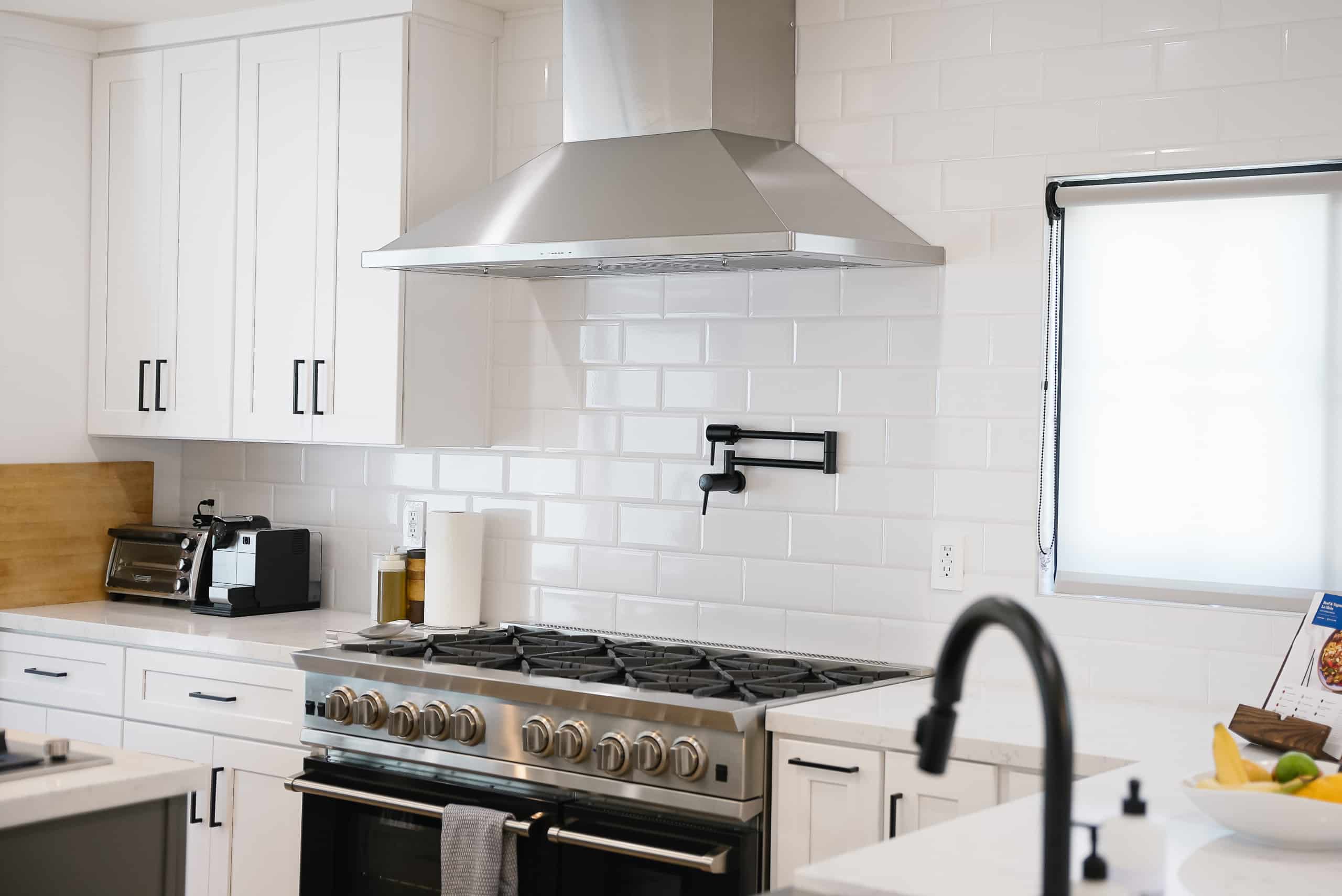 Finished custom white kitchen with island and modern range in the Barrington Ave home