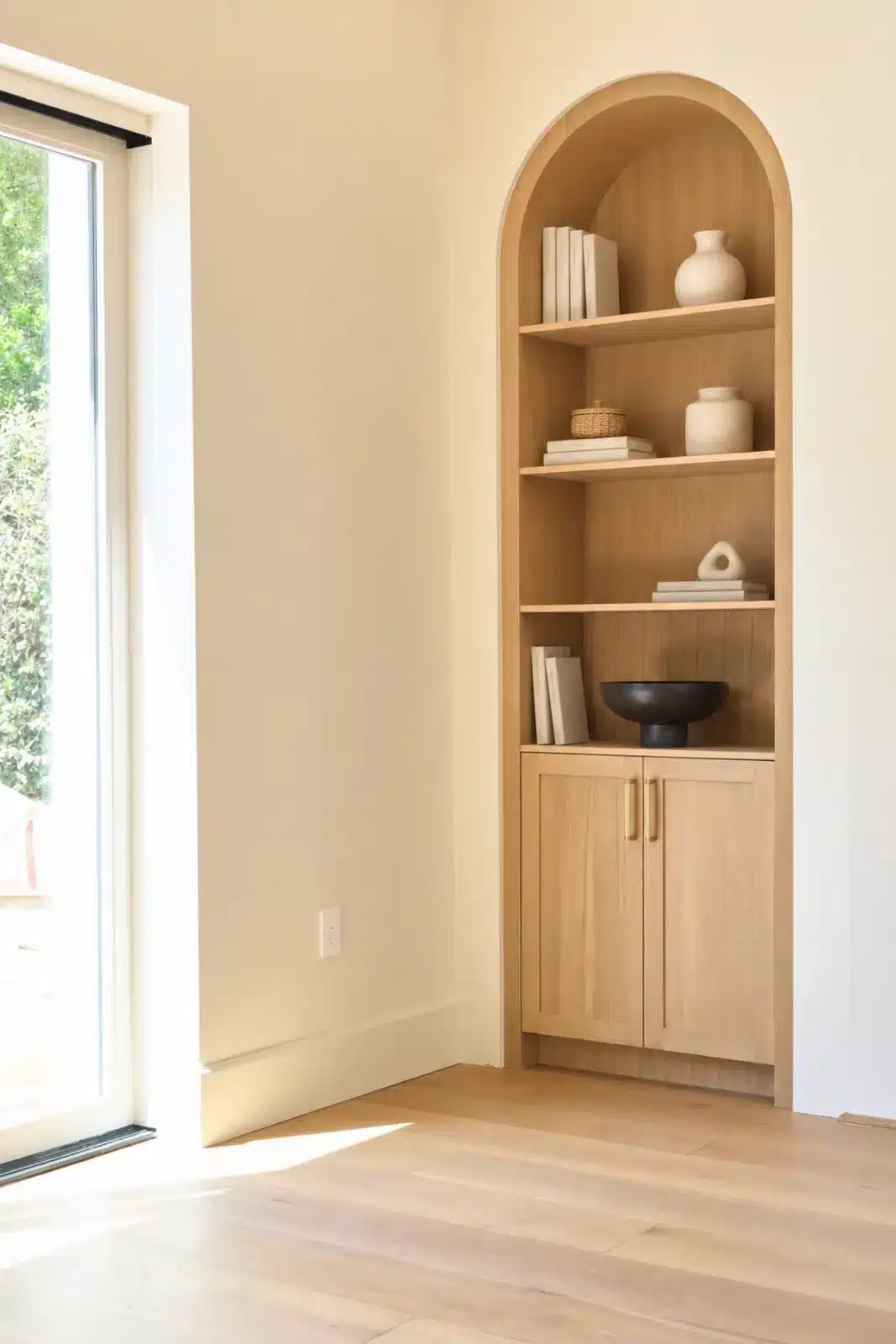 Arched oak built-in bookcase beside a sliding glass door