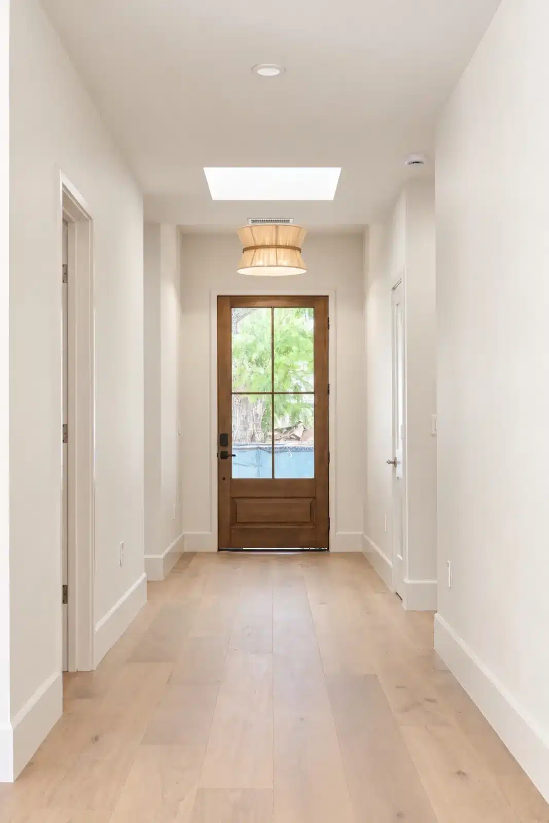 Hallway with wide-plank oak floors and skylight leading to the front door