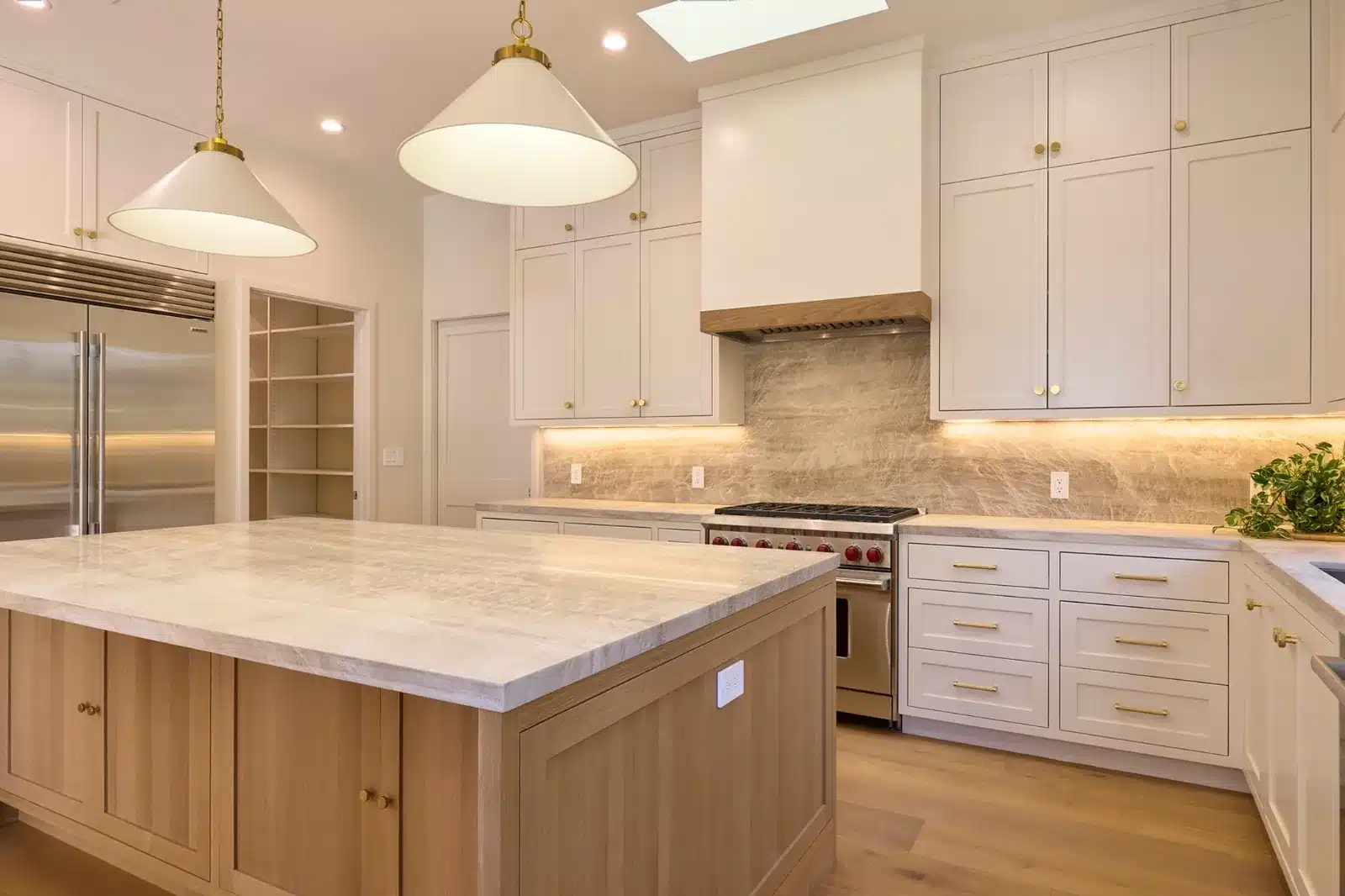 Kitchen island with quartzite top and oak base beside a professional range