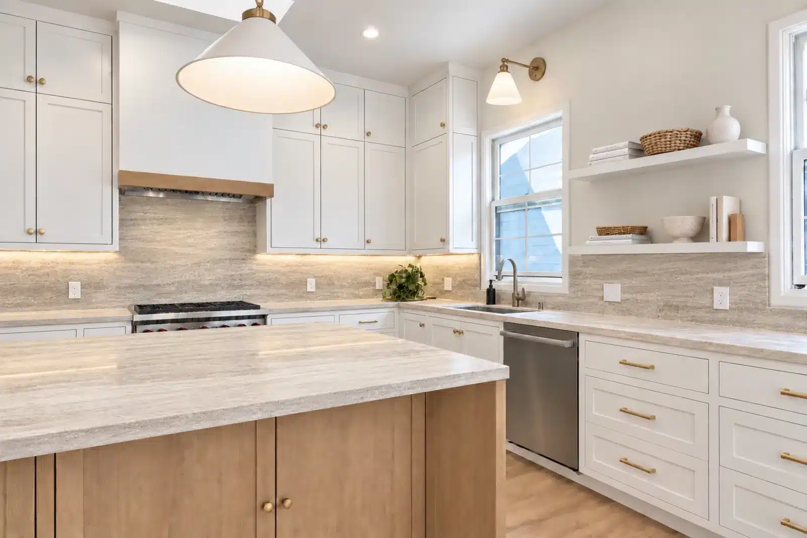 White kitchen with quartzite backsplash, range hood with oak trim and floating shelves