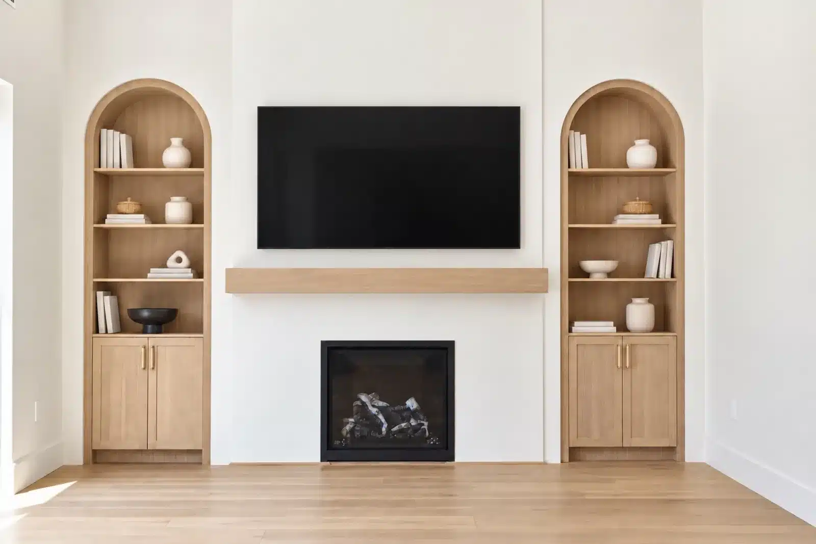 Living room with fireplace flanked by arched oak built-in shelving