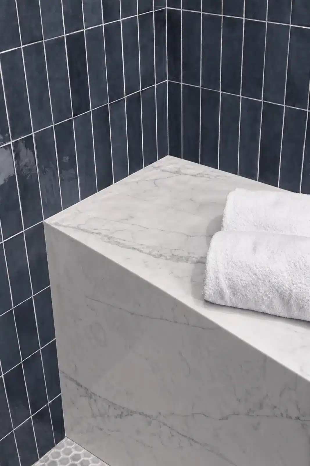 Marble shower bench with navy vertical tile