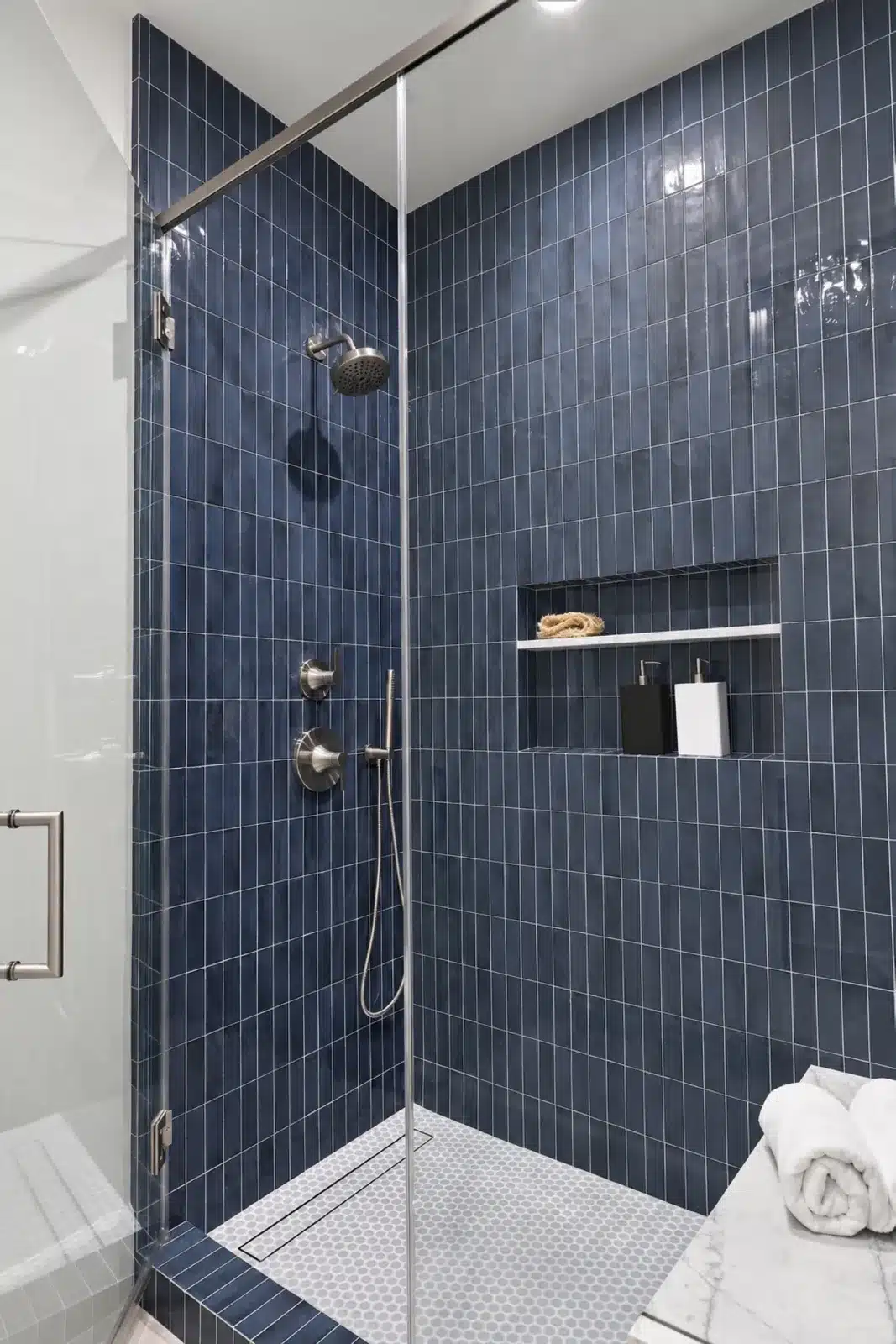 Glass shower with navy stacked tile and built-in niche