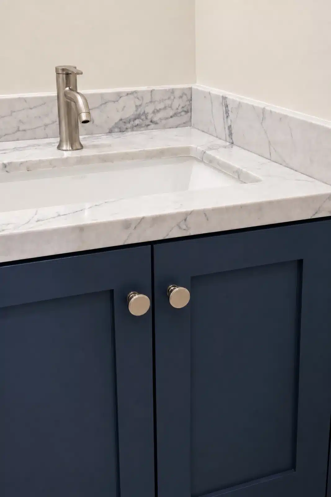 Navy shaker vanity with marble countertop and nickel faucet