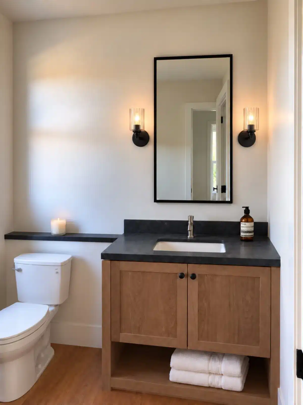 Powder room with oak vanity, black stone top and sconces